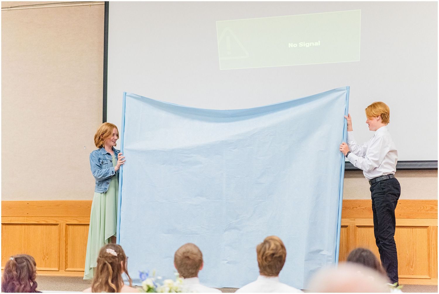 Two people holding light blue fabric during fun wedding reception game or activity.