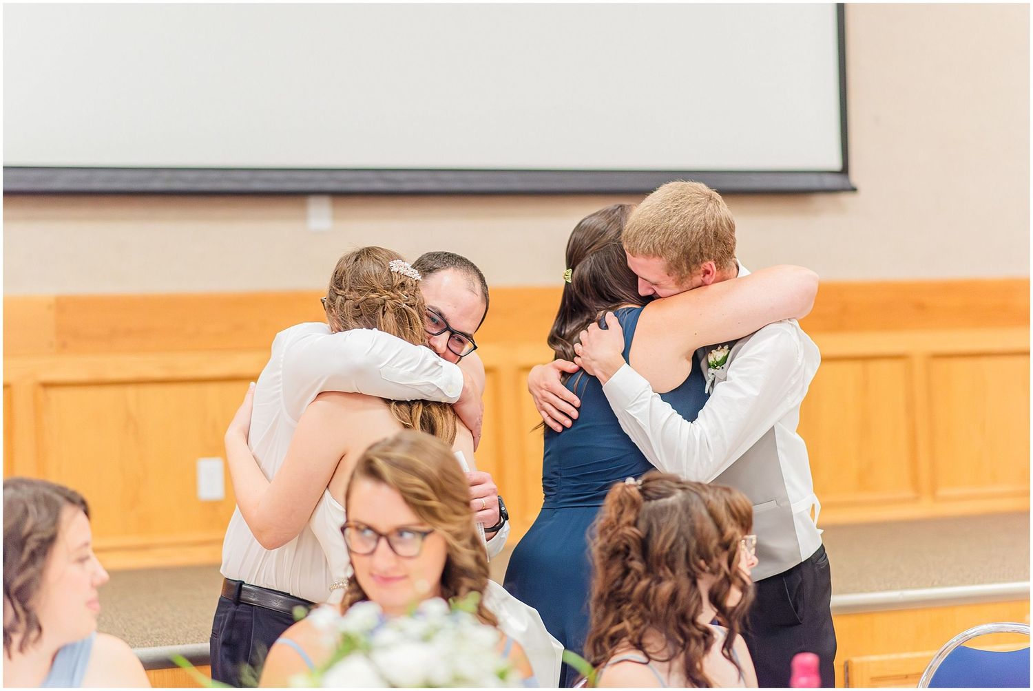 Guests sharing warm embraces during a wedding reception in an elegant venue.