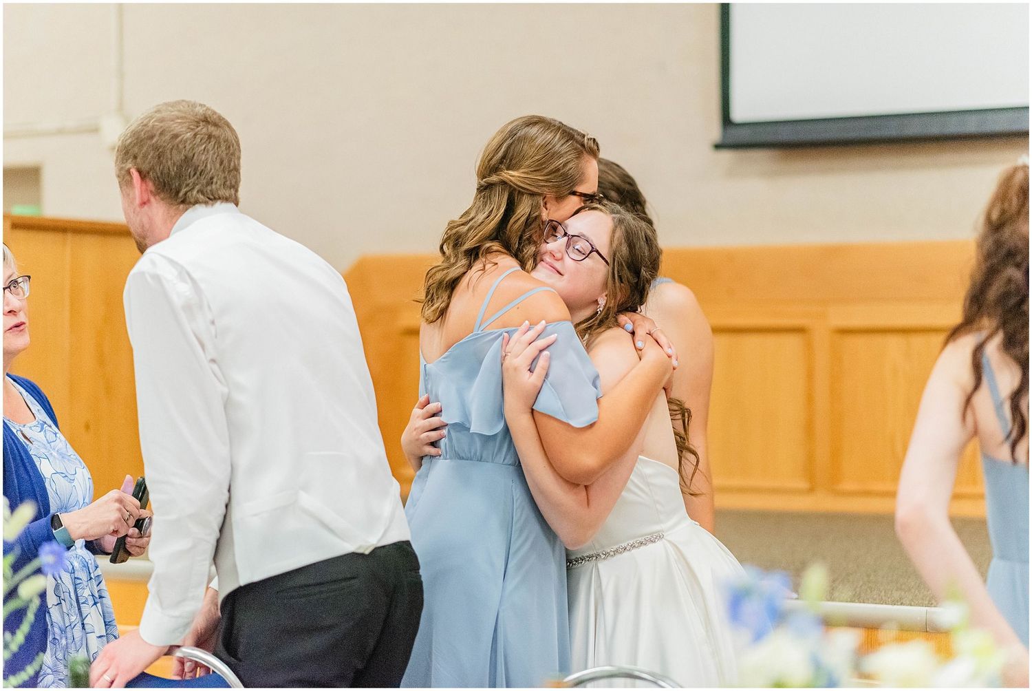 Two women in formal attire sharing a heartfelt hug at a wedding reception.