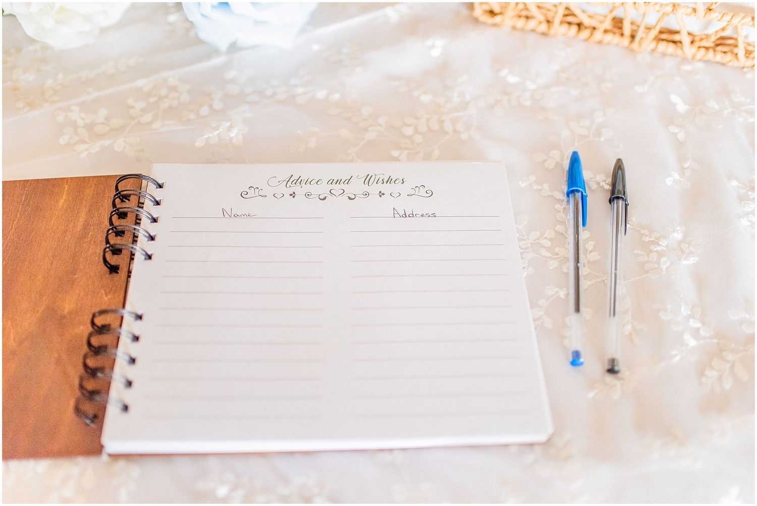 Wedding guest book open on decorated table with two pens ready for signatures at reception.