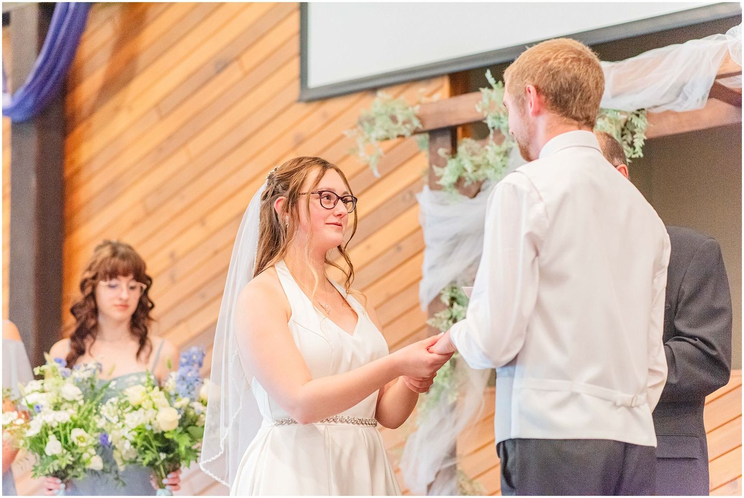 Bride and groom exchanging vows during wedding ceremony at rustic wooden chapel.