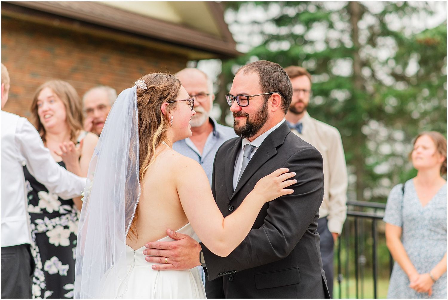 Bride and bearded groom sharing first embrace as married couple outdoors after ceremony.