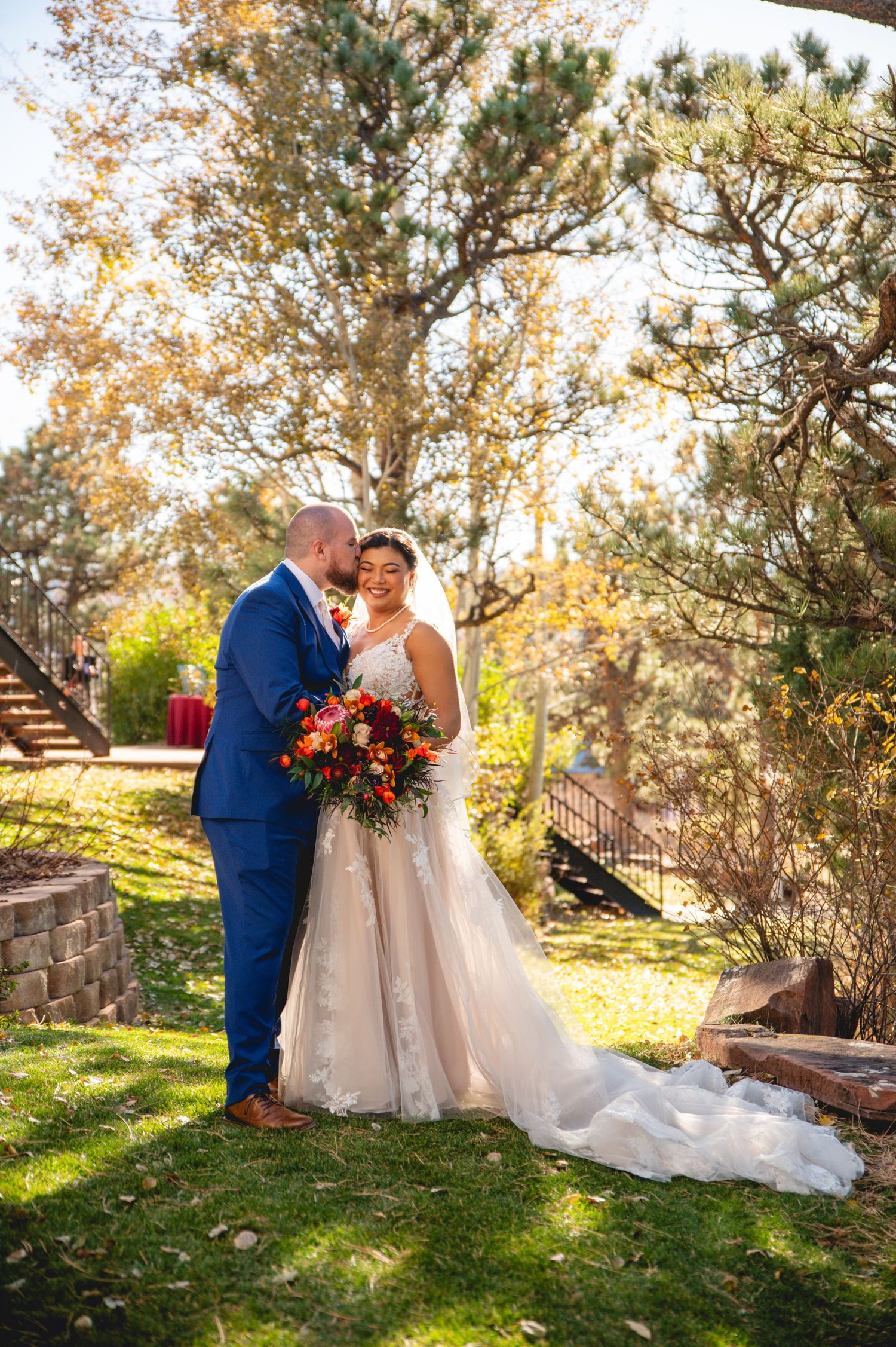 A couple sharing an intimate moment in autumn sunlight during their wedding portraits.