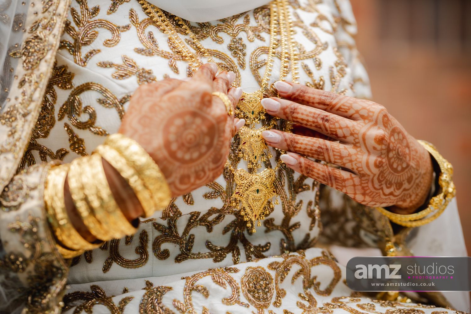 Bride's hands adorned with intricate henna mehndi and gold bangles in traditional South Asian bridal jewelry.