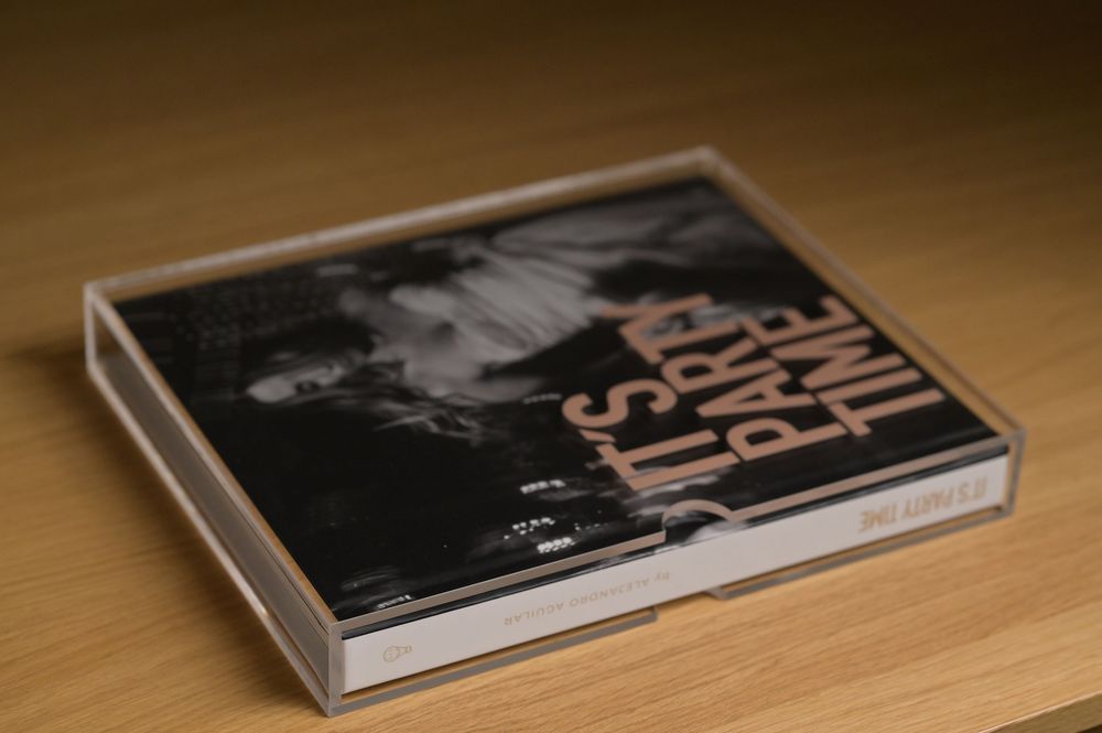Top view of Its Party Time photo book in clear acrylic display case on wooden table.