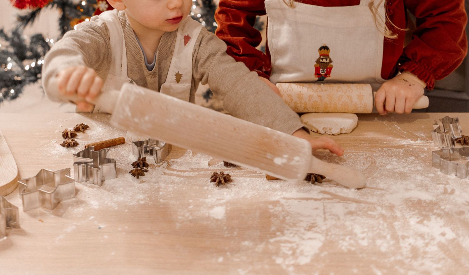Deux jeunes enfants pâtissant ensemble avec des rouleaux à pâtisserie, capturant un moment de complicité familiale authentique à domicile.
