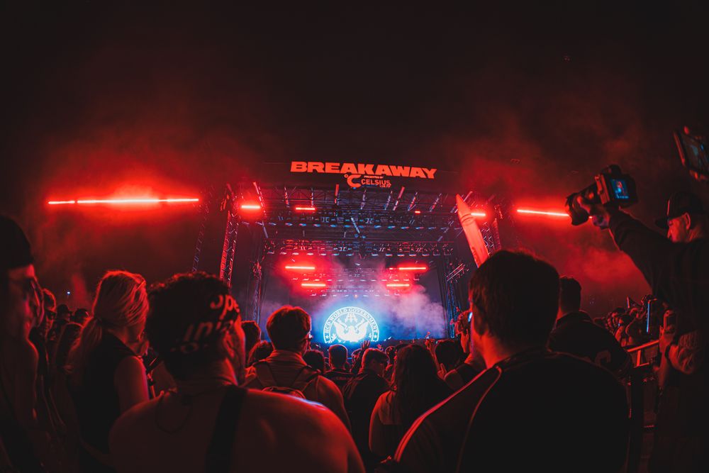 Crowd at Breakaway Music Festival under red stage lights and dramatic fog at an outdoor night concert.