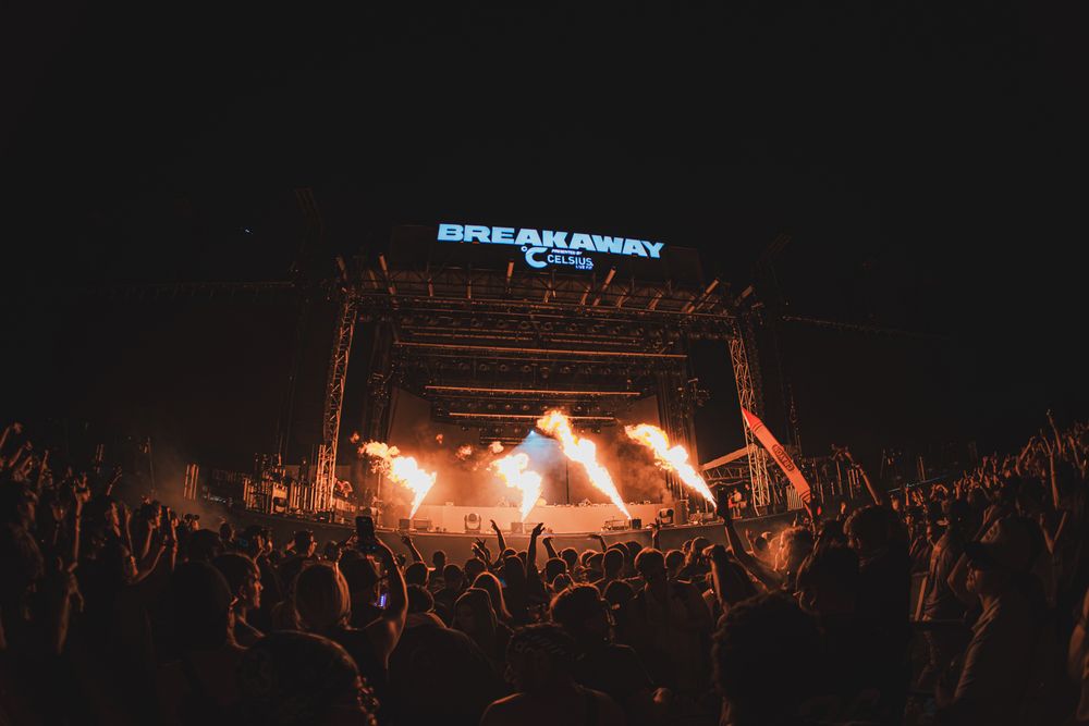 Breakaway Music Festival night show with massive crowd, fire effects, and illuminated stage under dark sky.