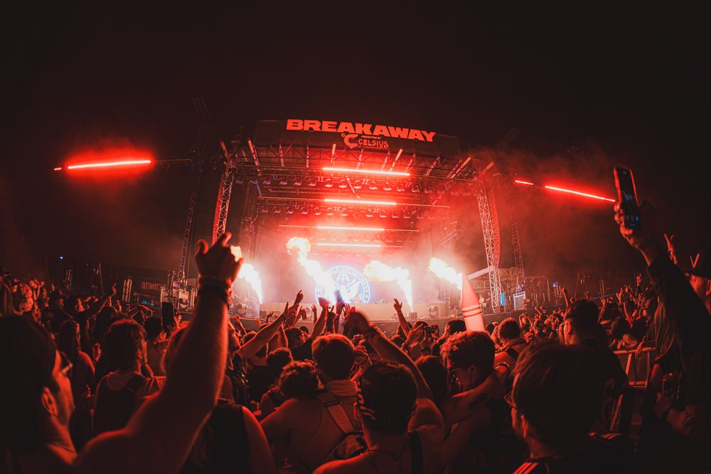 Breakaway Music Festival crowd bathed in red lights with hands raised at night.