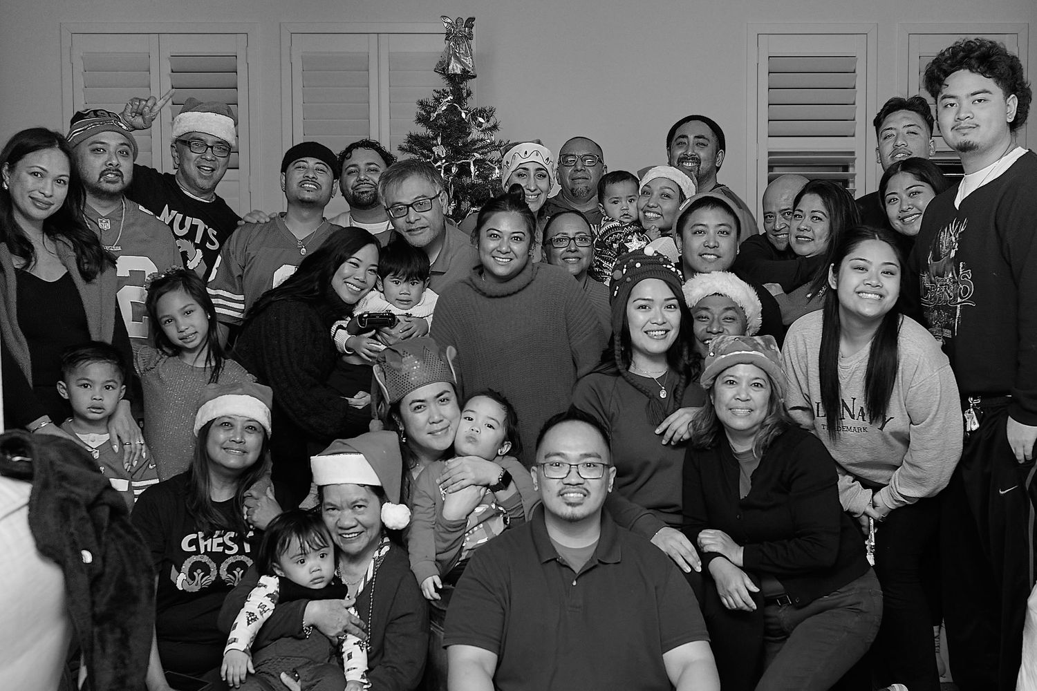 Large group holiday photo with people wearing festive red and green attire around a Christmas tree in in Pleasant Hill California.