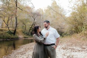 A couple shares intimate moments during a fall photoshoot by a creek.