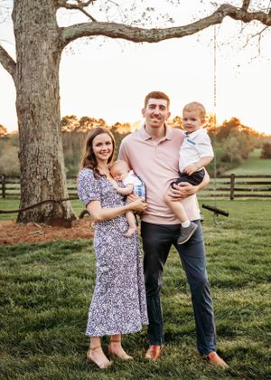 Family enjoys quality time together under large trees during golden hour.