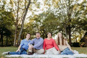 Group relaxing on blankets under autumn trees during golden hour.