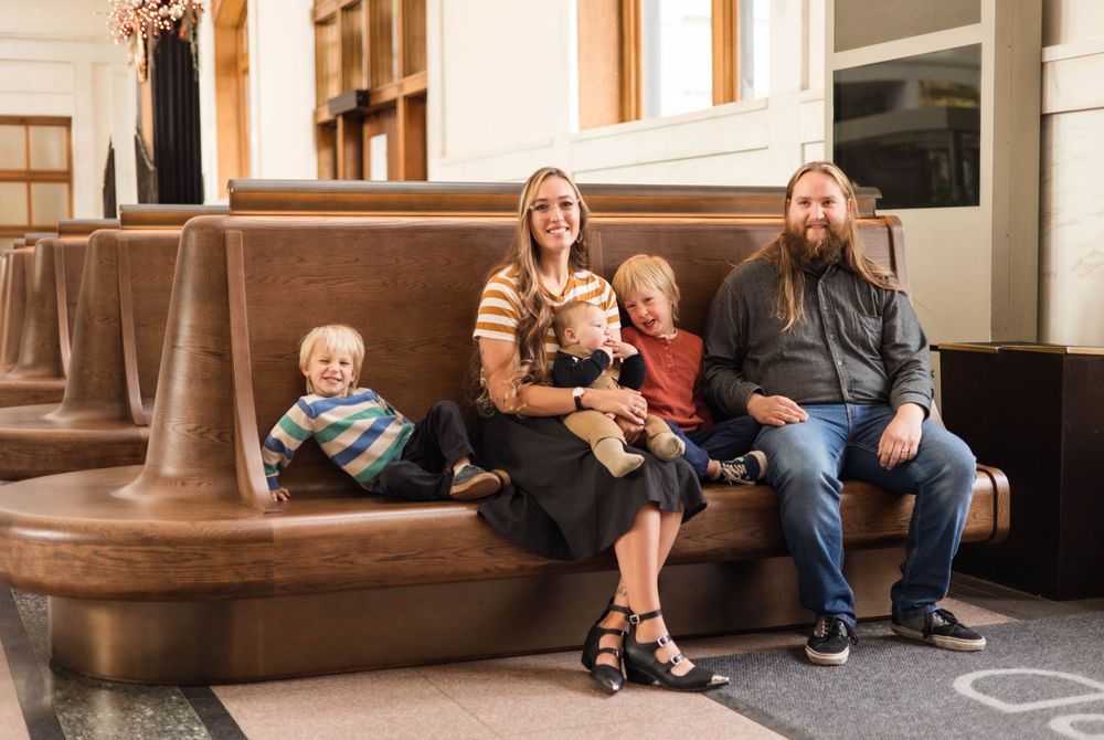 Family relaxing together on brown leather bench in indoor setting.