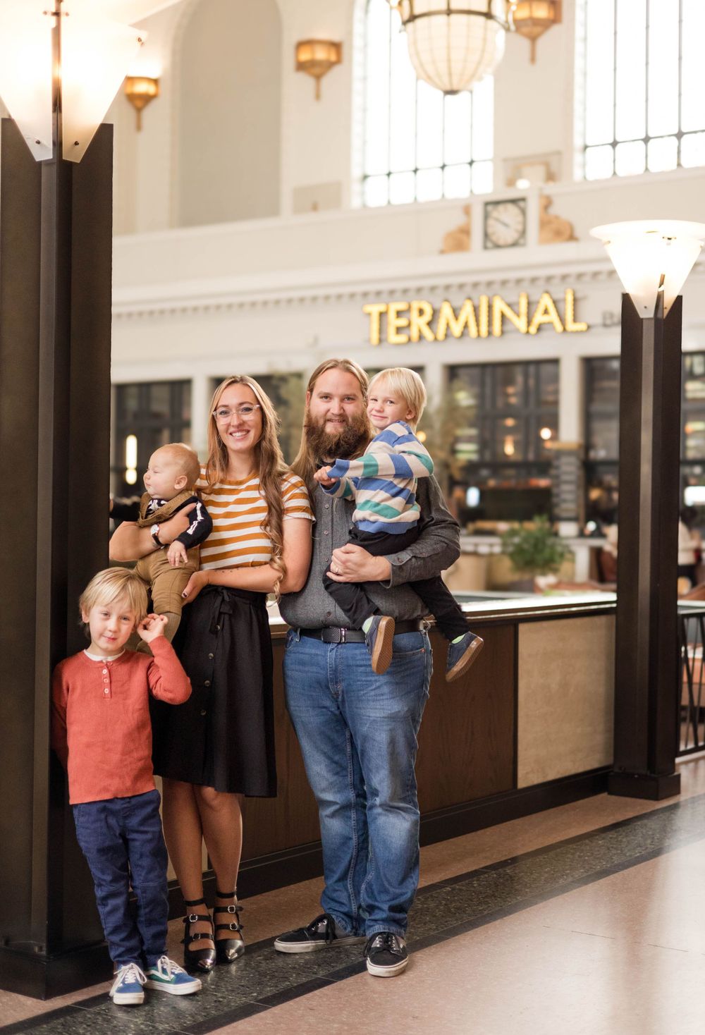 A family stands together in front of an illuminated Terminal sign in an indoor venue.