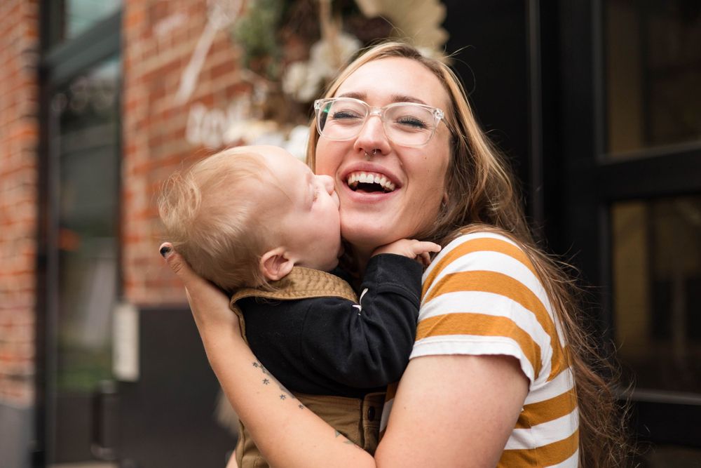 A joyful moment shared between parent and infant against a brick wall backdrop.