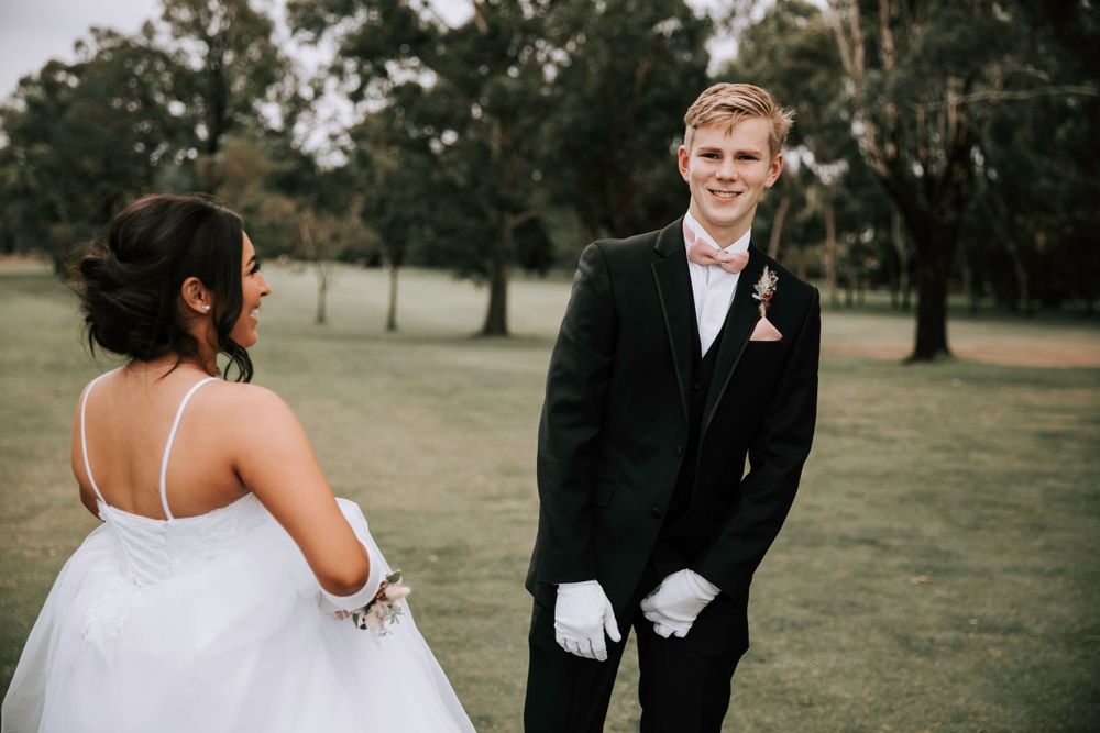 Wedding couple sharing a lighthearted moment on a golf course.