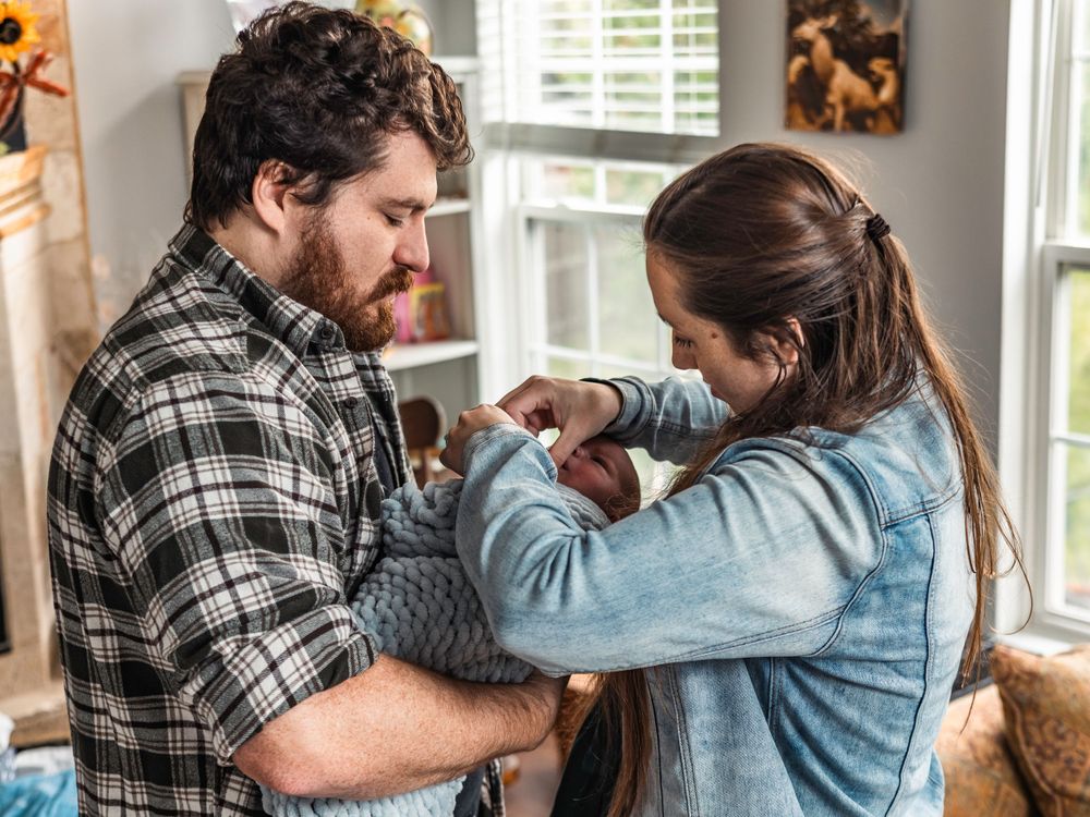 Two parents share tender moment while holding their newborn baby.