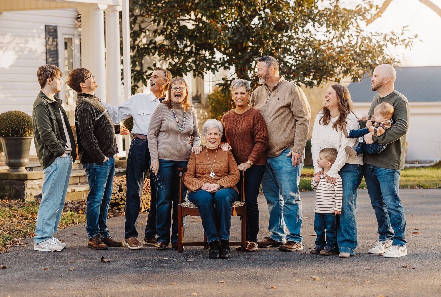 Extended family gathering outdoors for group photo on autumn day.
