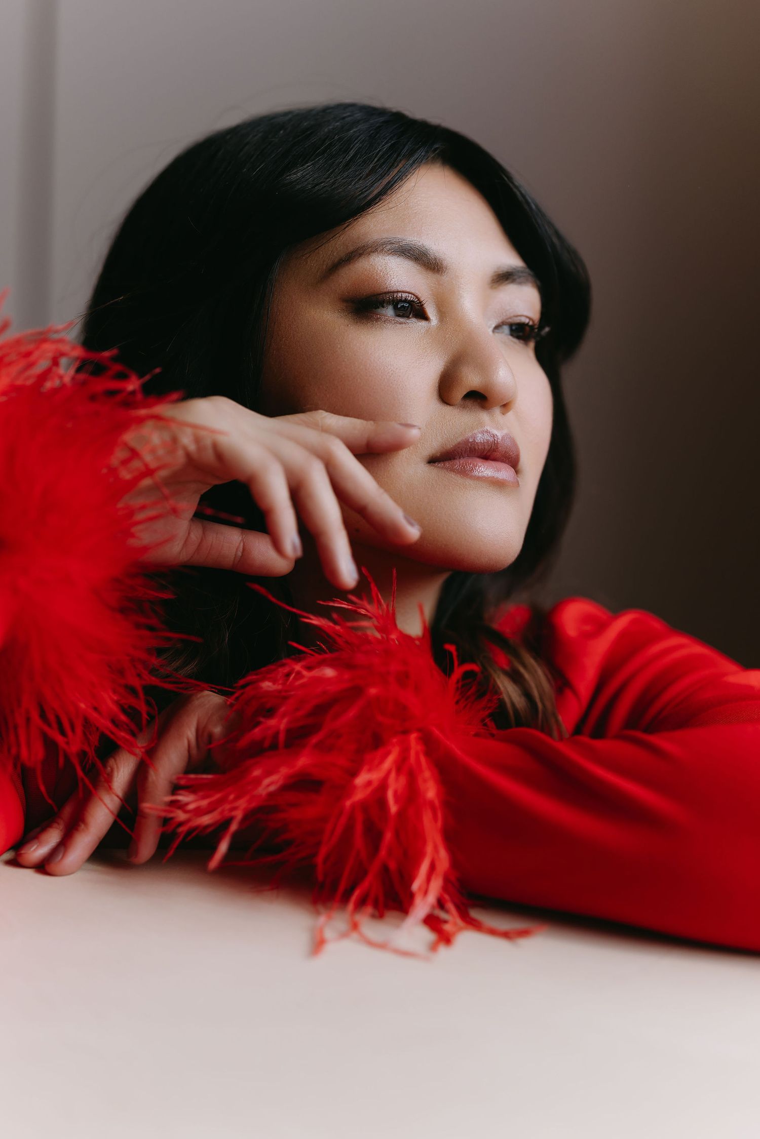 Striking portrait with red feathered detail against dark background.