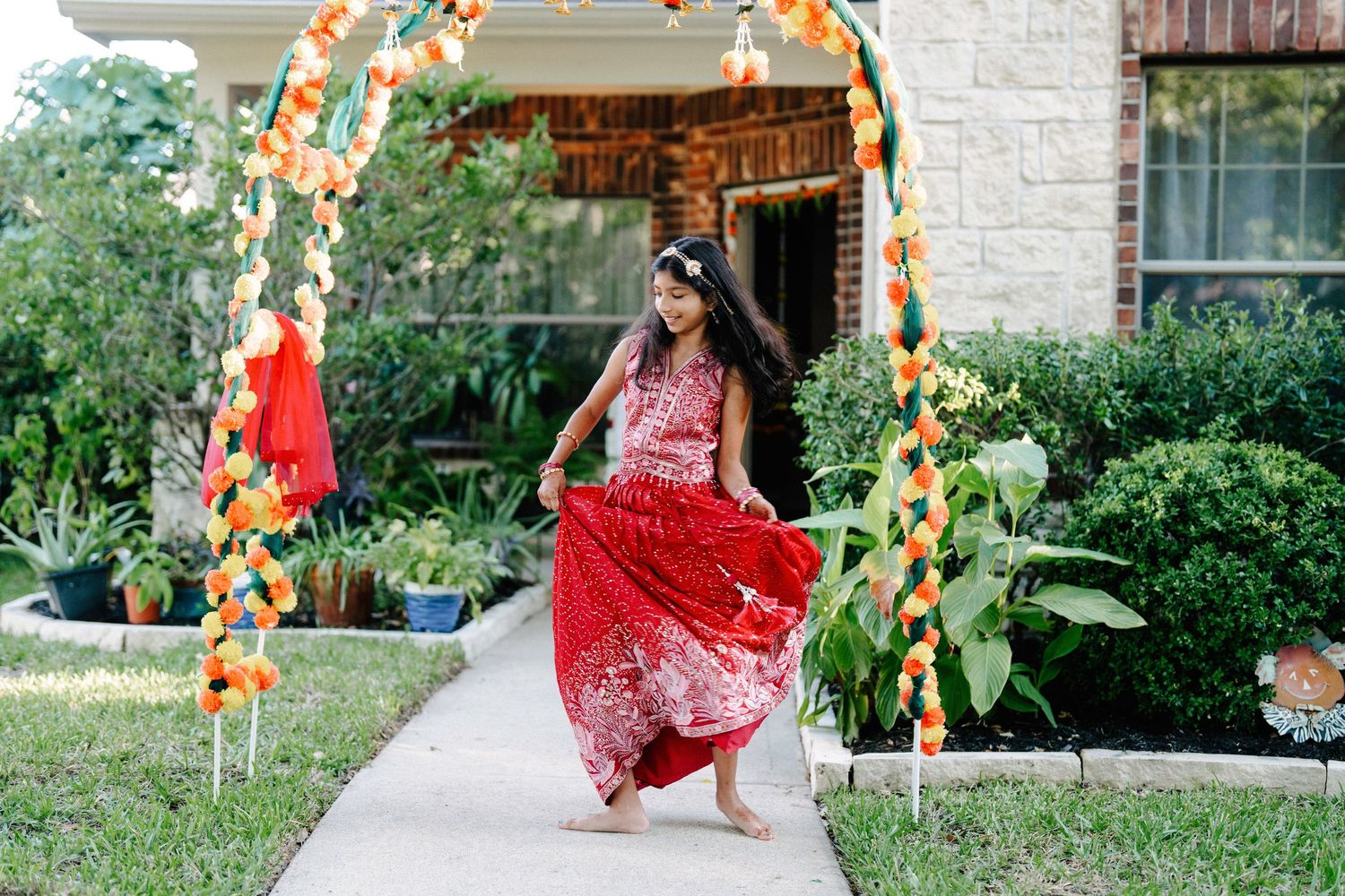 Colorful outdoor celebration with orange and white balloon decorations and floral arrangements in a garden setting.