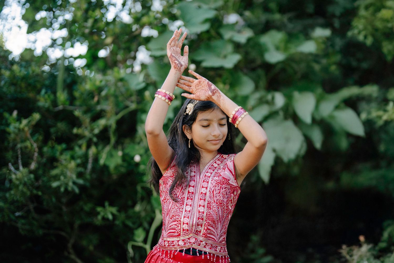 Traditional Indian dance performance in an outdoor garden setting with colorful red attire.