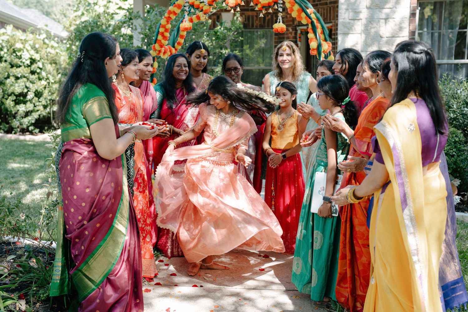 A group of women in colorful traditional Indian saris gather outdoors for a celebratory moment during a cultural event.