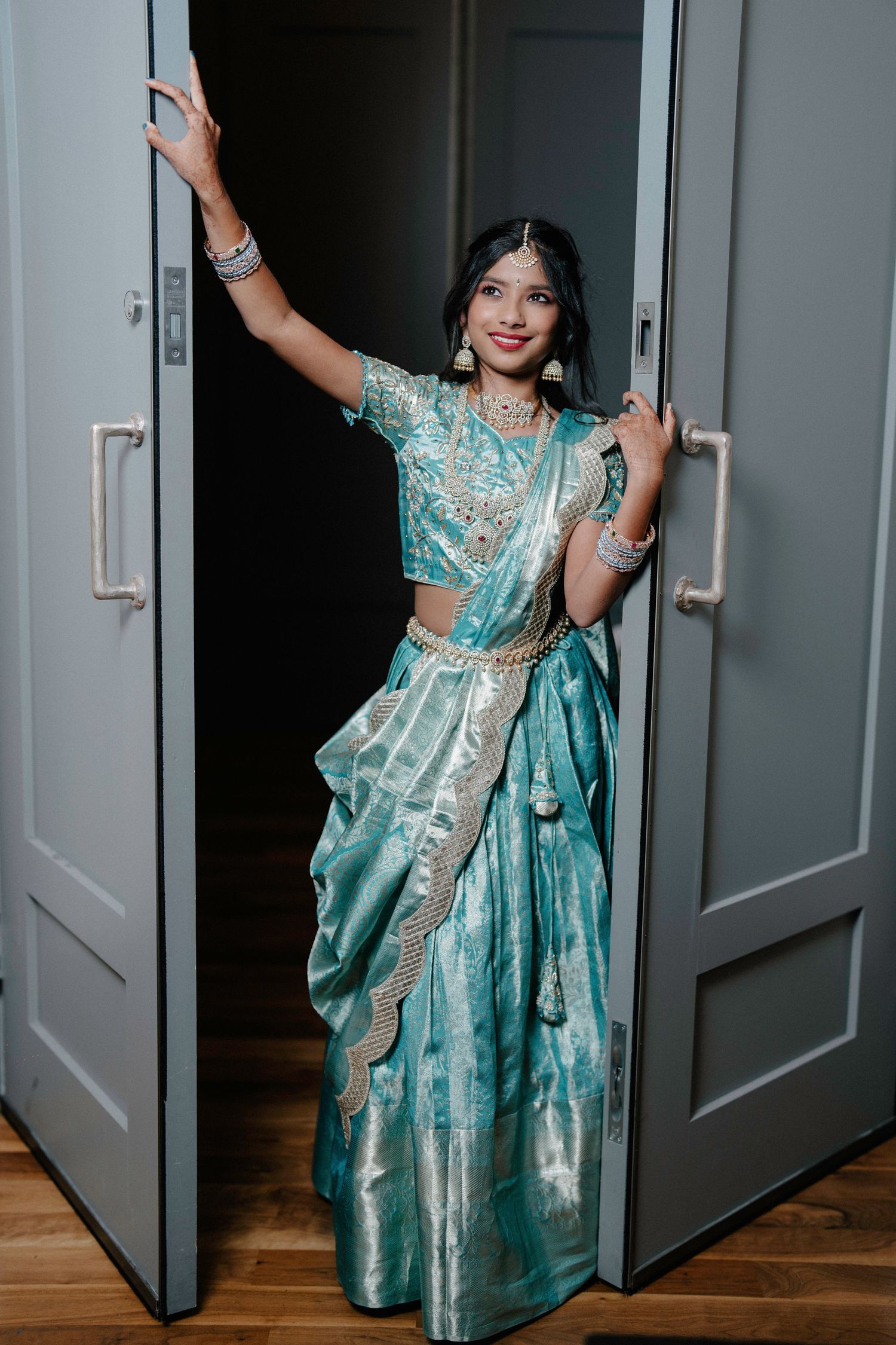 Dynamic photo sequence showing twirls and movements in a turquoise silk saree against grey doors.