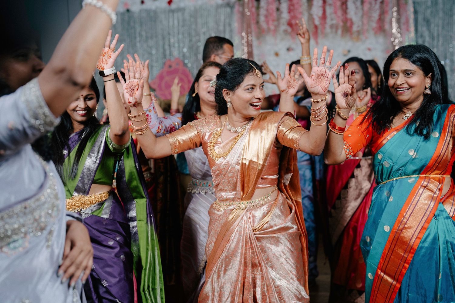 Guests in colorful traditional Indian attire dance together during a festive celebration.