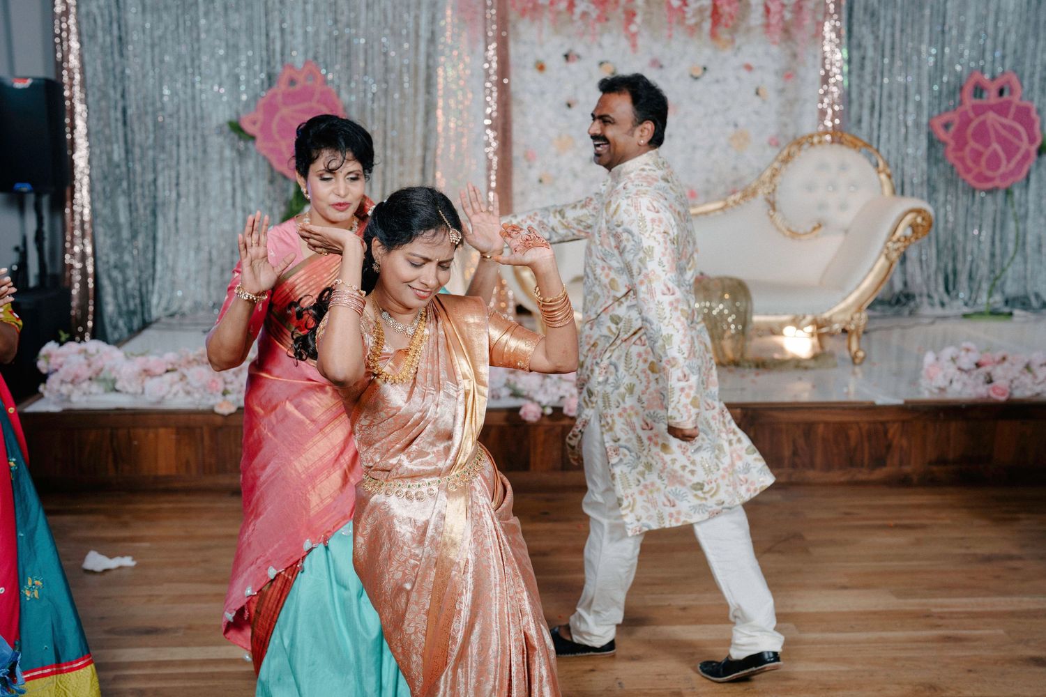 Wedding celebration with guests in vibrant formal attire dancing together.