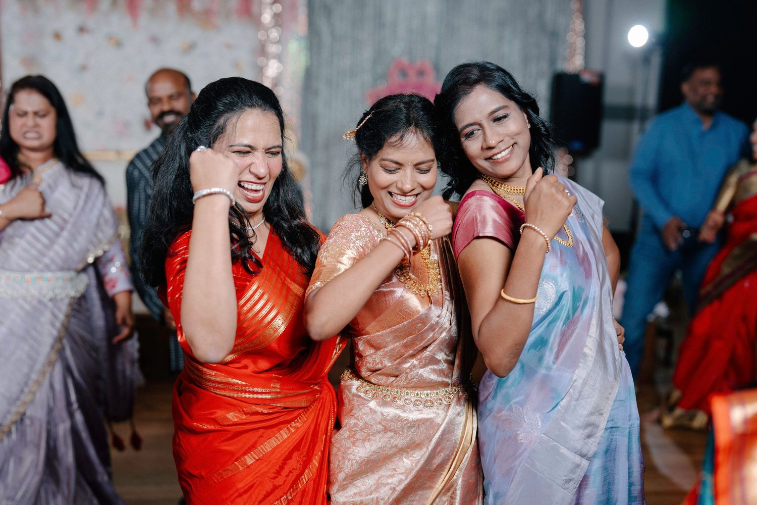 Wedding celebration scene with guests in colorful traditional saris dancing and enjoying festivities.