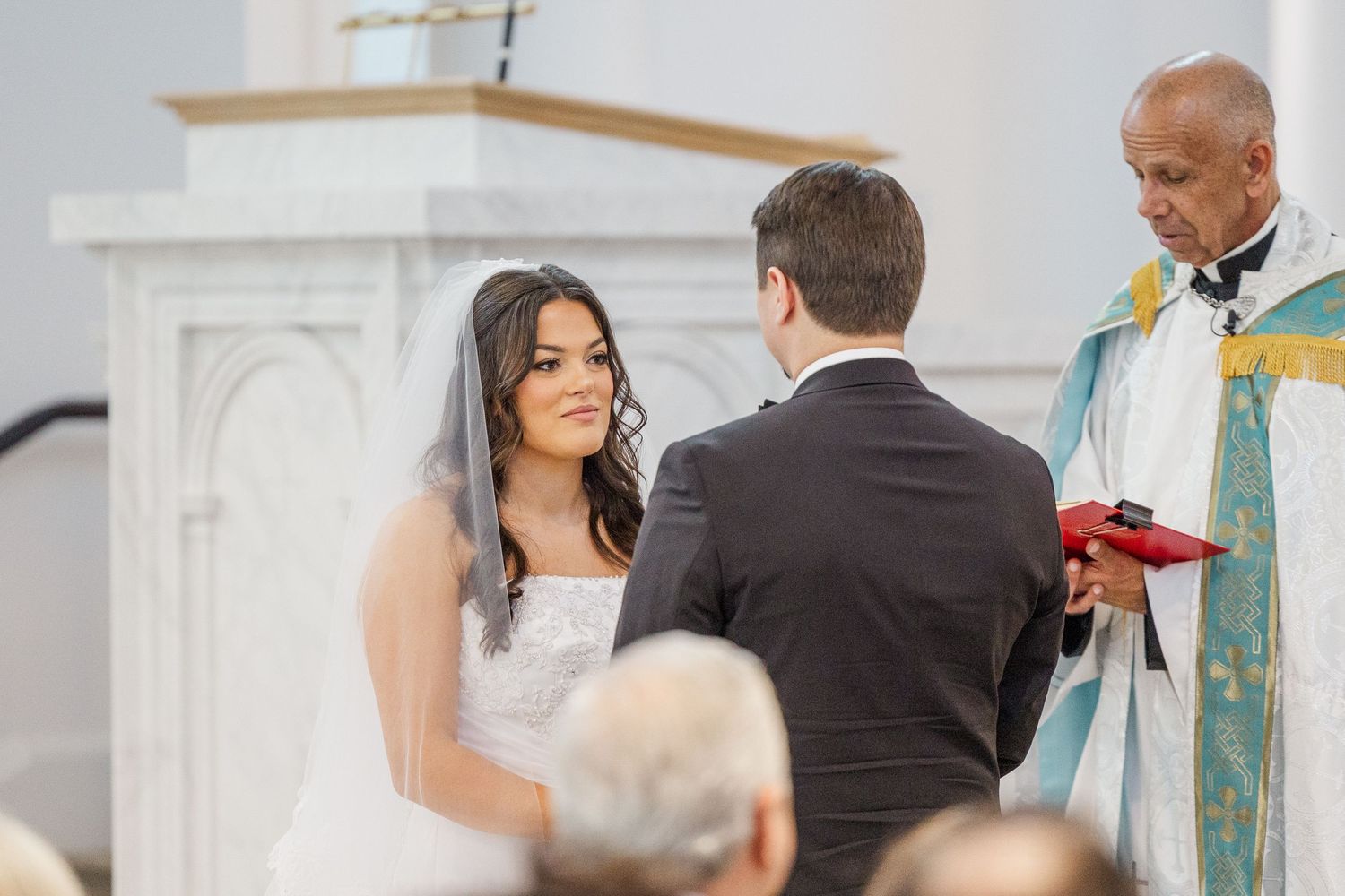 A couple shares a romantic dance moment during their wedding celebration in an elegant white-draped venue.