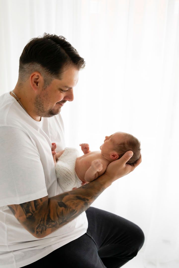 Vastasyntynyt vauva nukkuu rauhallisesti, kapaloituna kauniiseen vaaleaan liinaan, Newborn kuvaaja Muurame, vauva mahtuu isän kämmenille