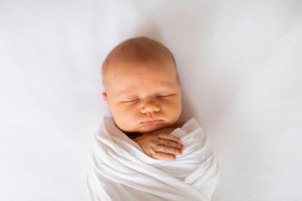 Vastasyntynyt vauva nukkuu rauhallisesti vaaleassa kapalossa, newborn kuvaus Jyväskylä, Muurame