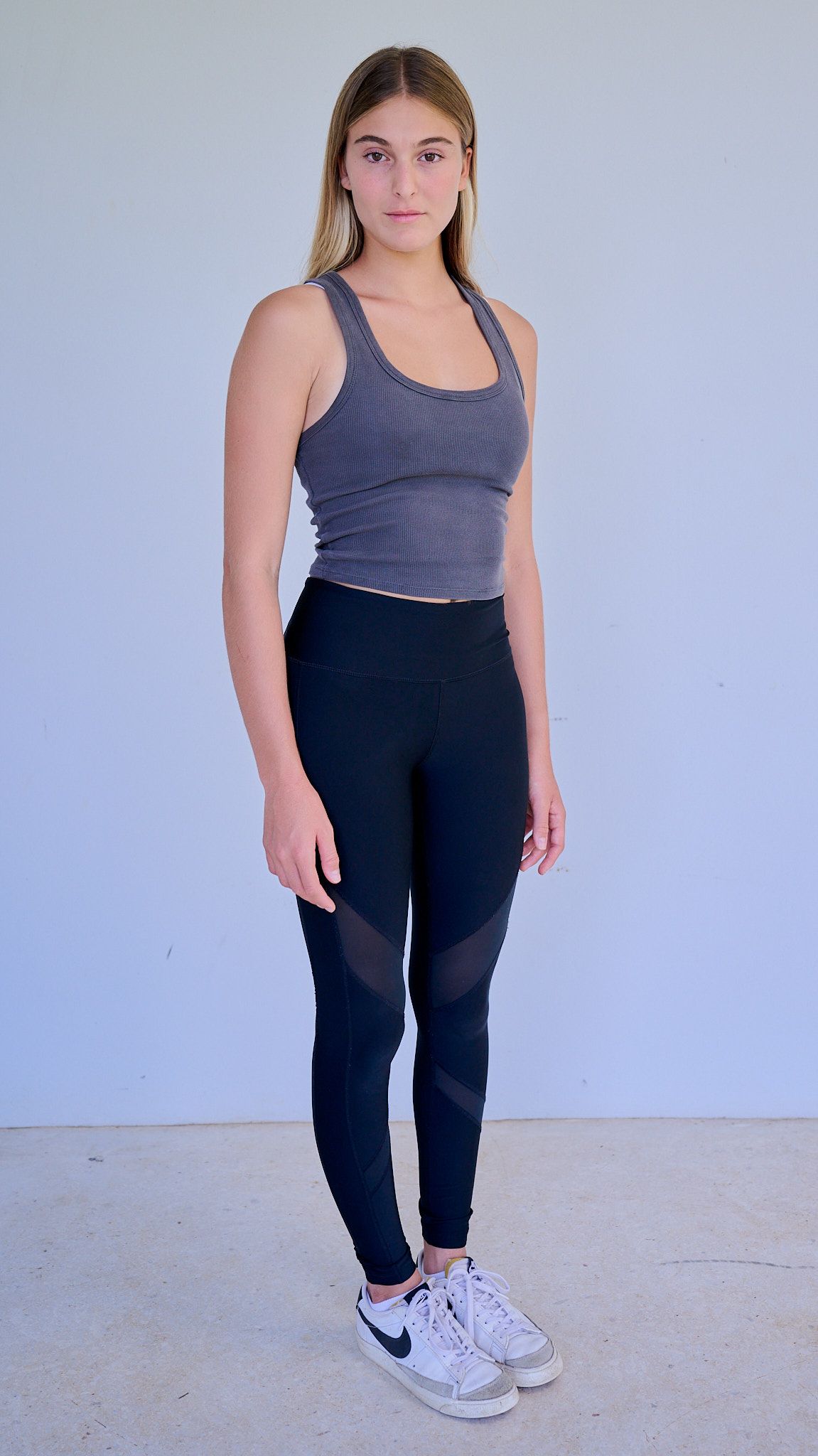 Model in white crop top and baggy blue jeans poses on black stool against light background.