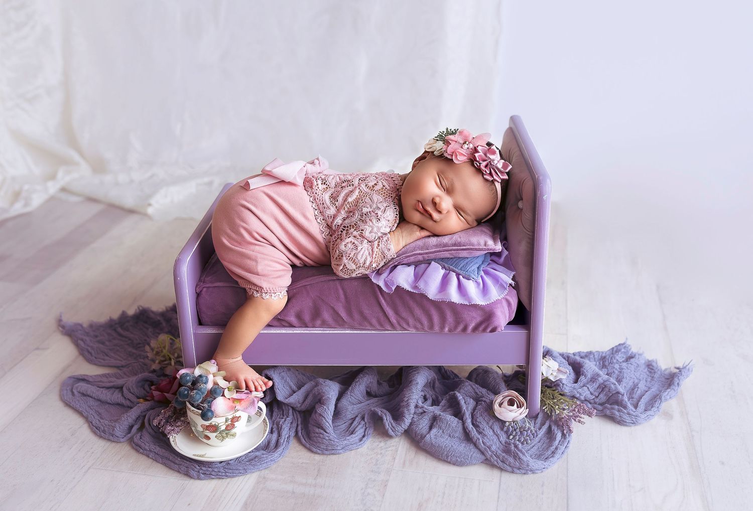 bebe duermiendo mientras sonrie en una cama color purpura
