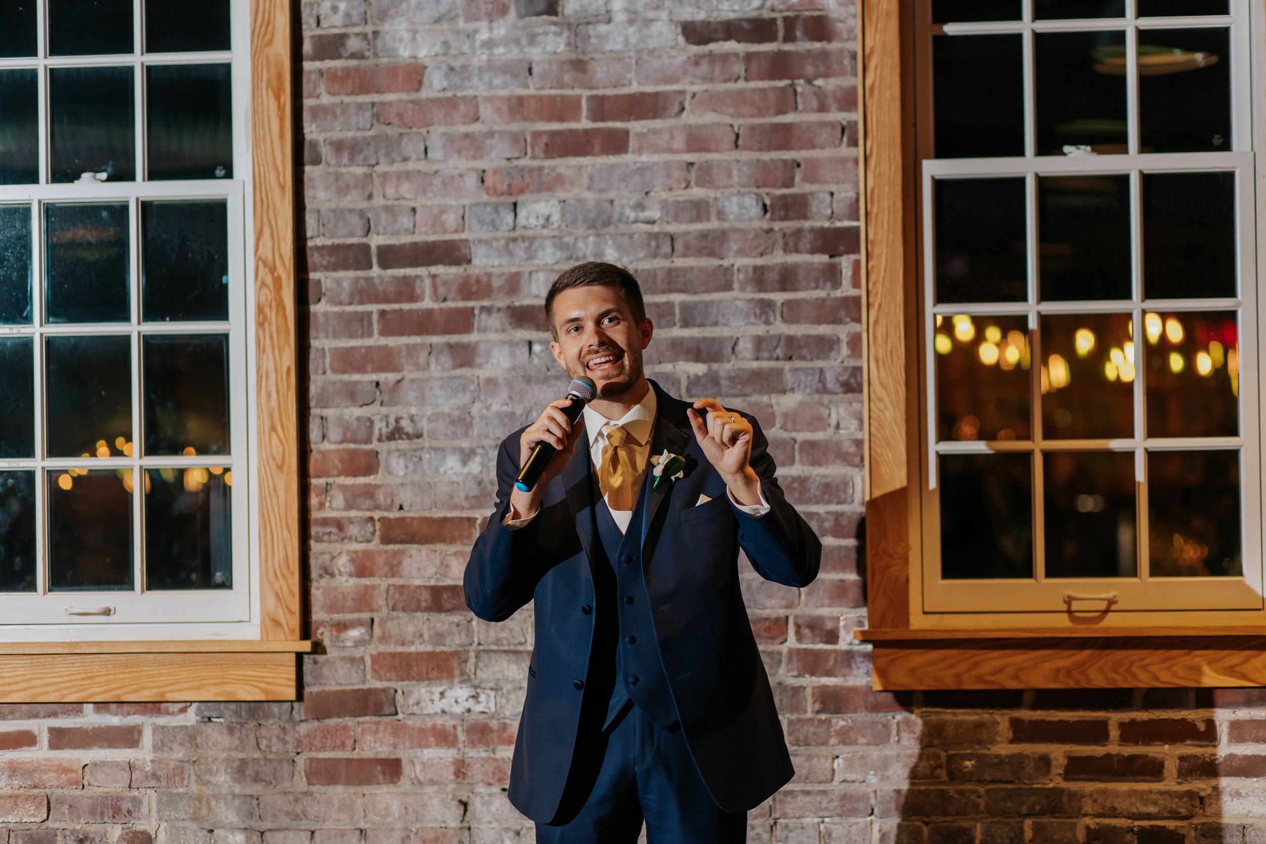 Interior of rustic brick venue with large windows and string lights creating warm ambiance.