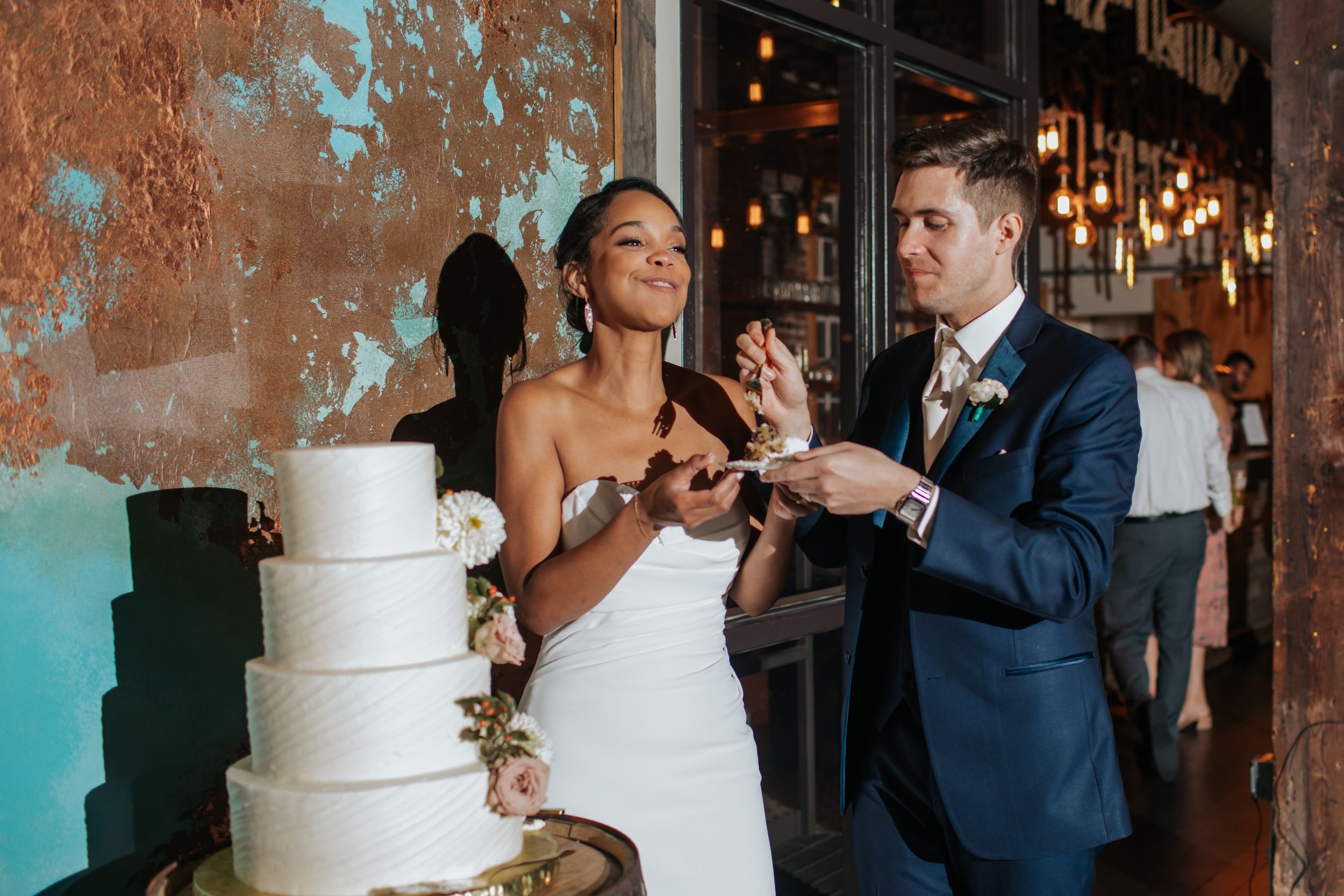 A wedding couple cuts their elegant white tiered cake together at their reception celebration.