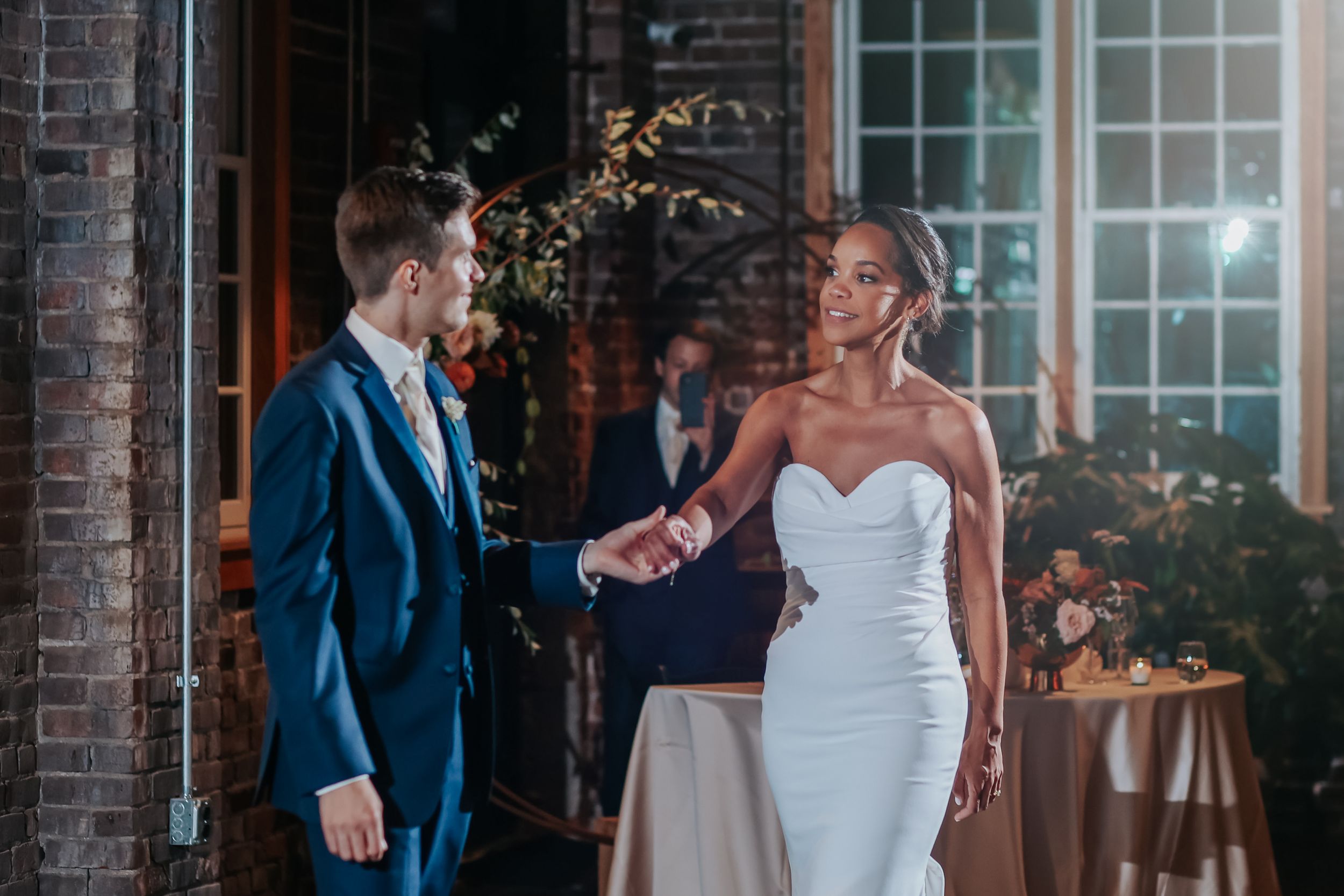 A bride and groom share a joyful moment together during their wedding celebration at a brick venue.