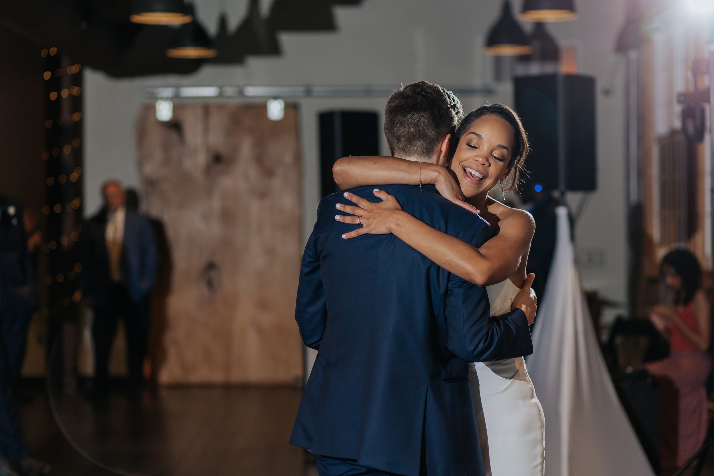 Couple sharing an intimate dance moment in a dimly lit reception space.