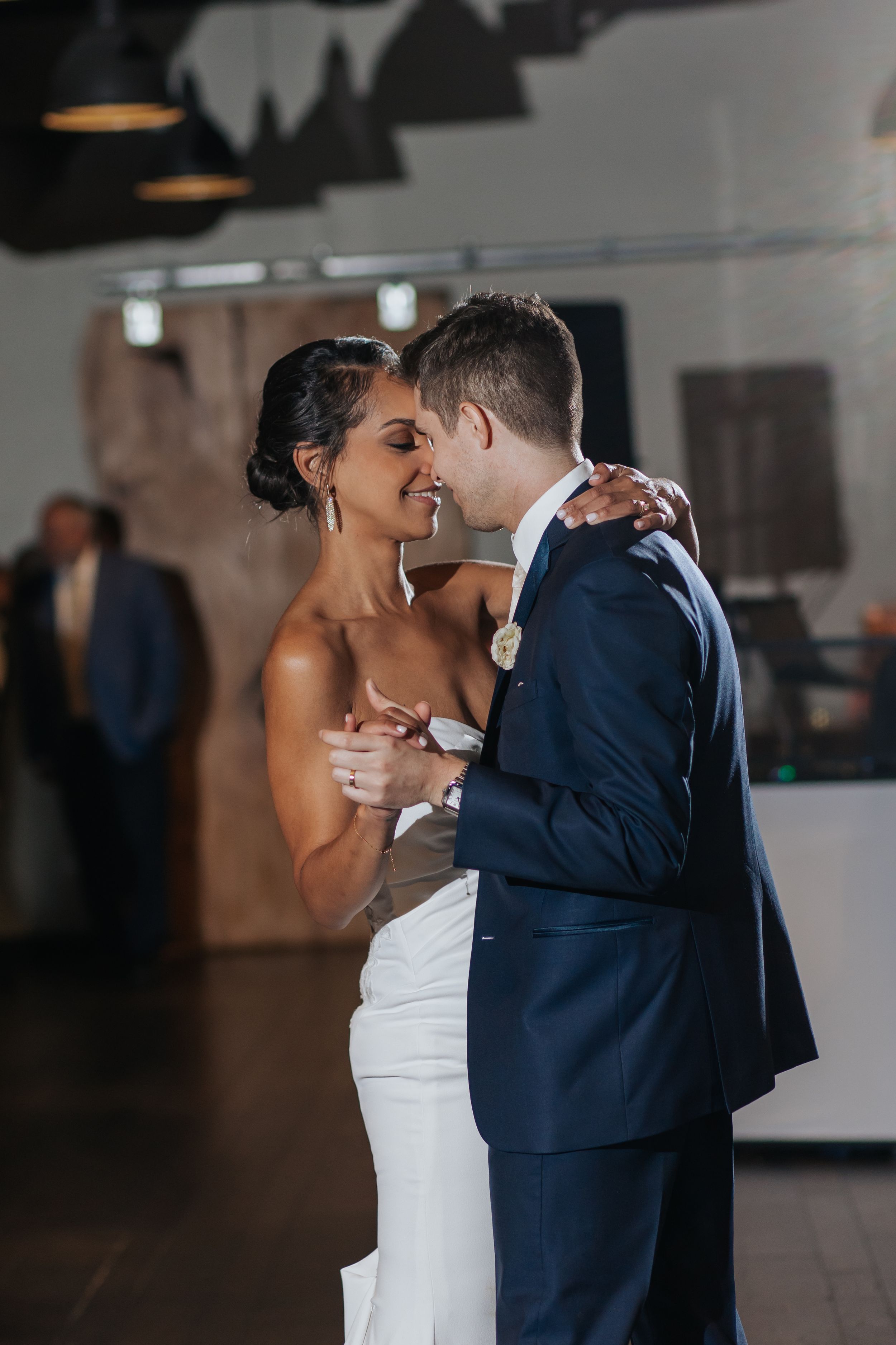 A romantic first dance moment at an indoor wedding reception venue.