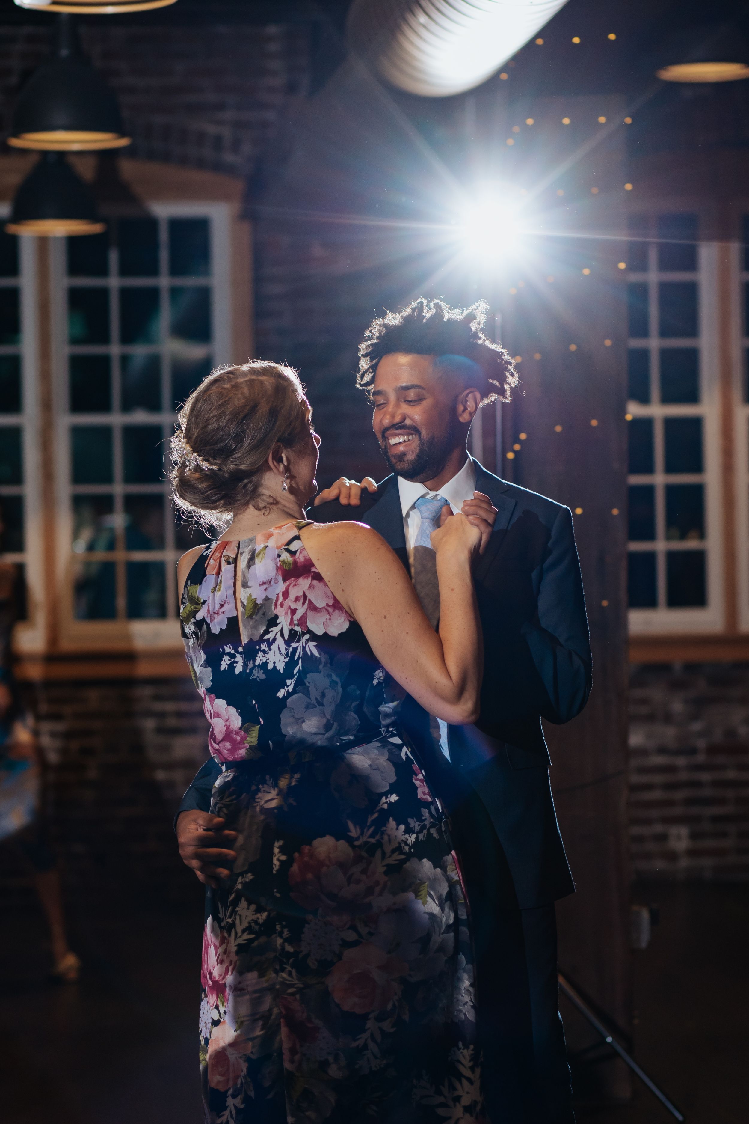 Dancing figures in a dark reception space with dramatic backlighting and exposed brick walls.