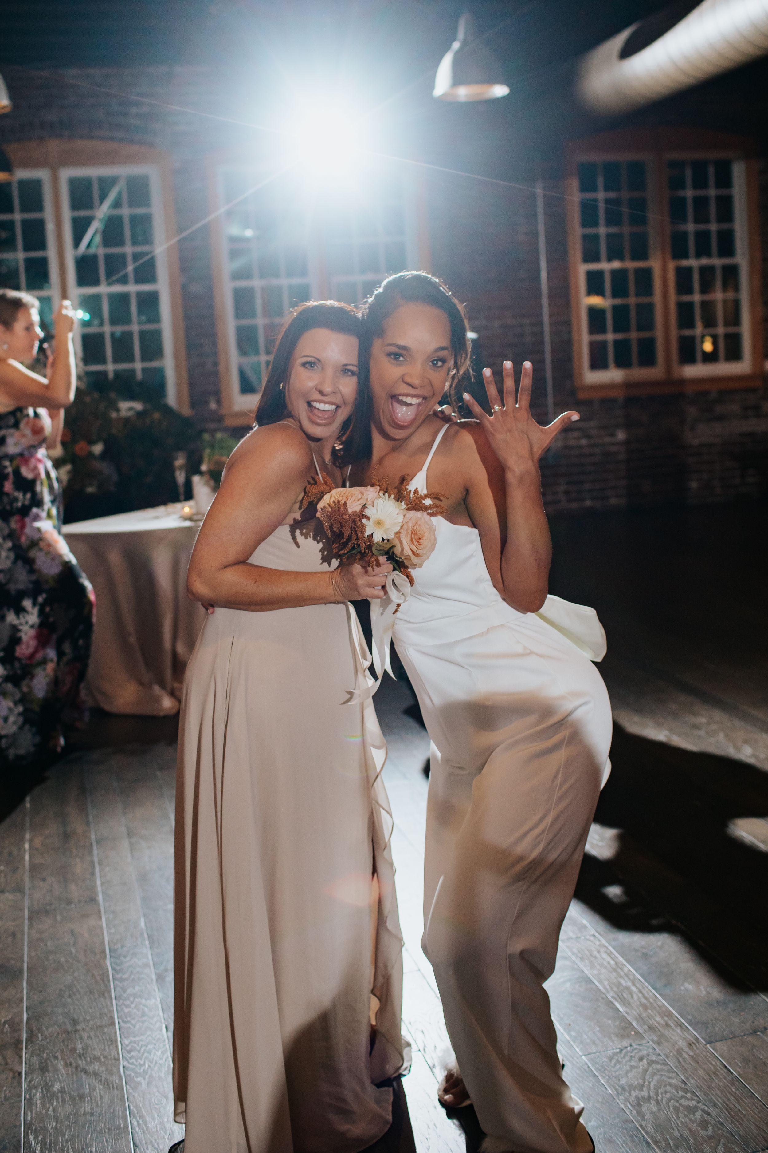 Bridesmaids in blush dresses dancing and celebrating at a wedding reception.