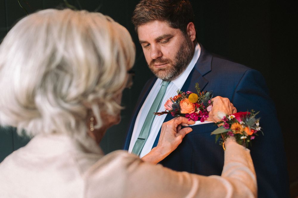 A couple shares an intimate moment during a wedding ceremony with colorful floral boutonnieres and bouquets.