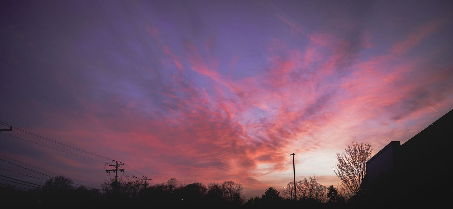 Sunset over city skyline silhouetted against bright winter sky.