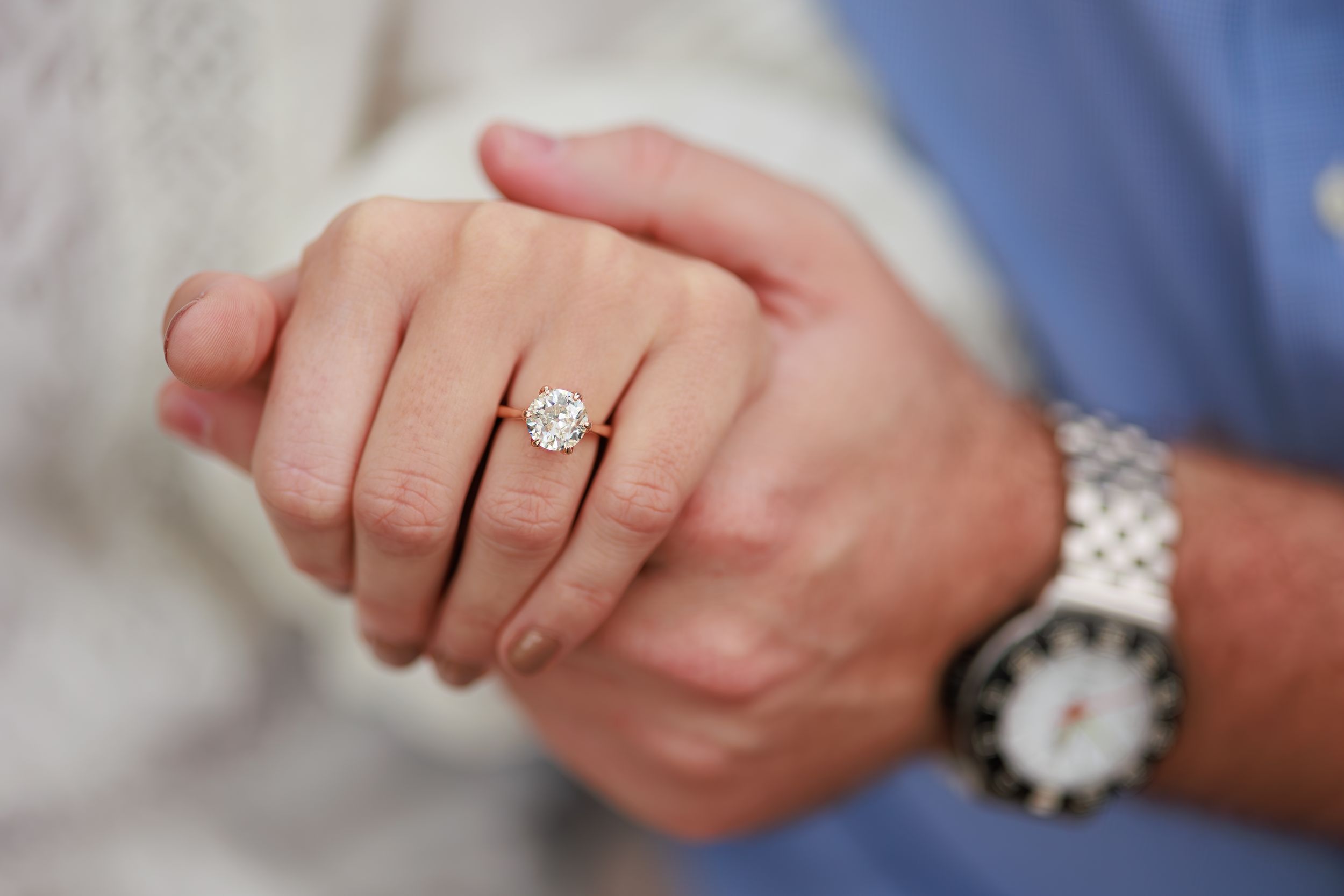 Close-up view of an engagement ring on a finger with a sparkling diamond solitaire in a silver setting.