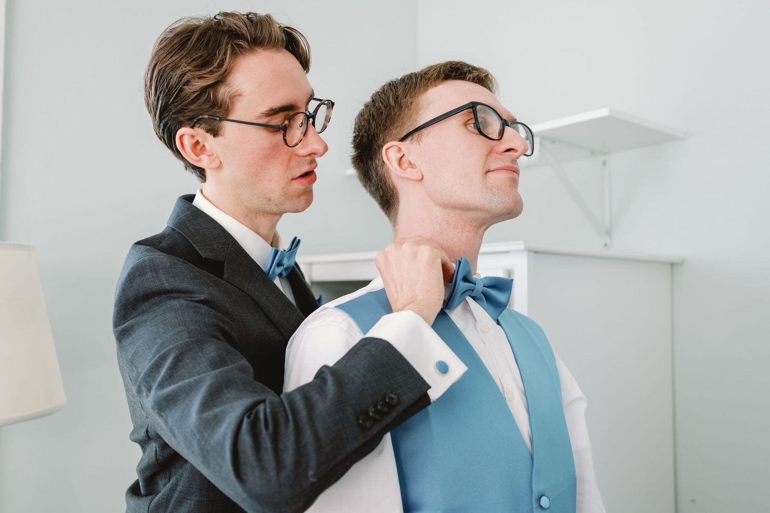 Two people in business attire embrace in an office setting with white walls and modern decor.