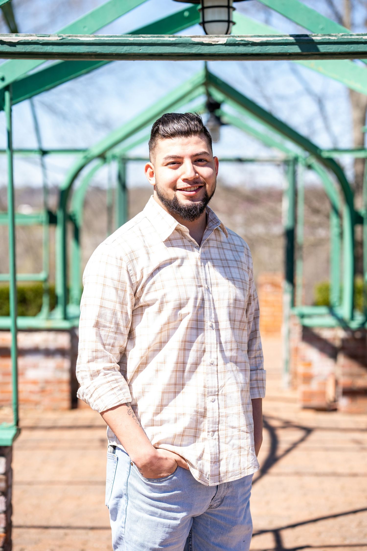 Senior portrait of a college student standing in front of a greenhouse.