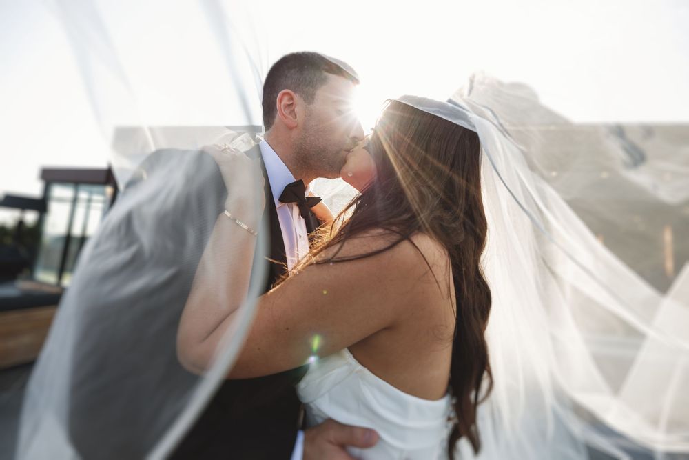 Sunlit wedding portrait with flowing veil creating romantic atmosphere.