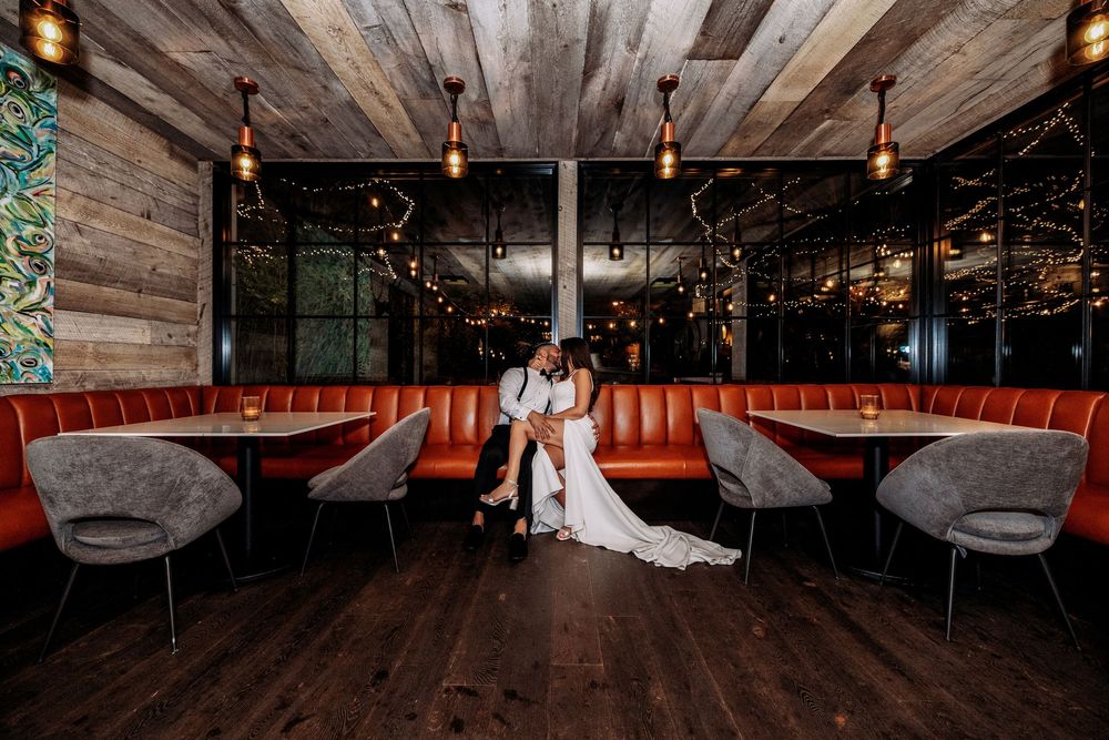 Wedding venue interior with rustic wooden ceiling beams and warm pendant lighting.